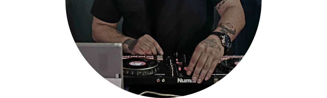 Close-up of a Wedding DJ with tattoos and Demali&RiverCo jewelry at a wedding reception playlist event.