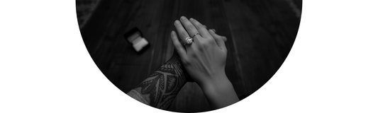 An intimate At-Home Proposal with a Diamond Engagement Ring and a hand with intricate tattoos — Demali&RiverCo.