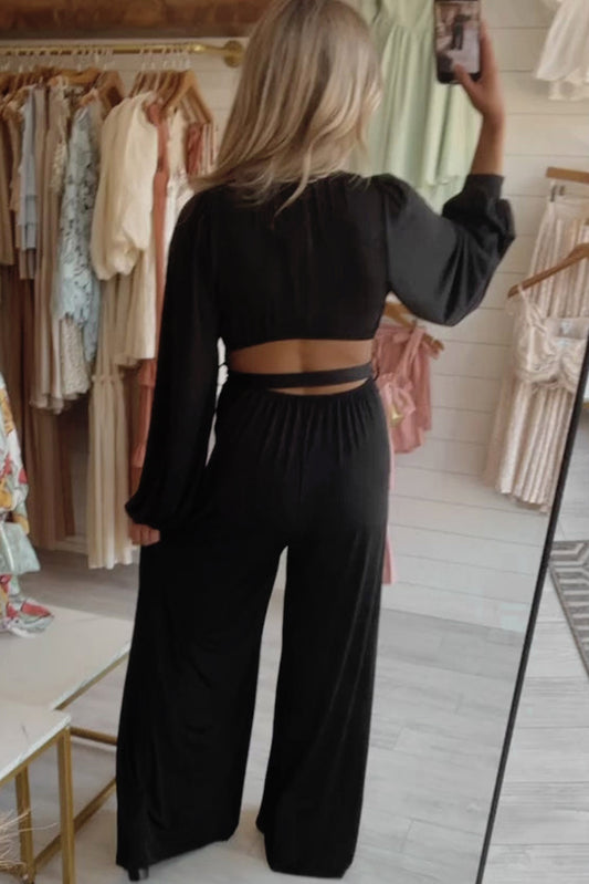 The Tejas - Jumpsuit features a sophisticated and stylish design with a deep V-cut back, perfectly accentuated with a belted waist and wide leg silhouette, making it a bold and alluring choice.